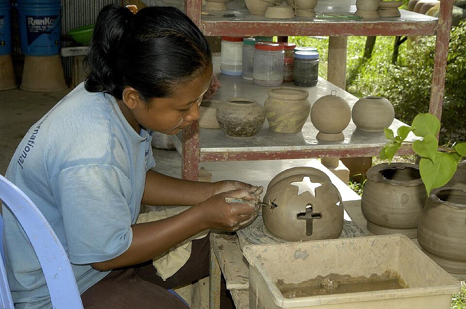 A Cambodian woman hand-building a ceramic vessel using traditional coiling technique