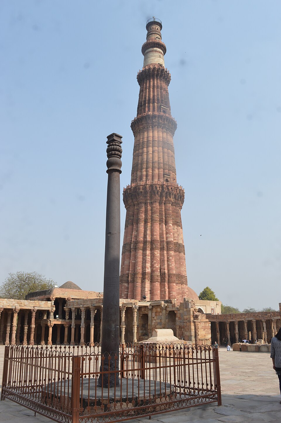 The Iron Pillar of Delhi standing in the Qutb complex, with the Qutb Minar visible behind it