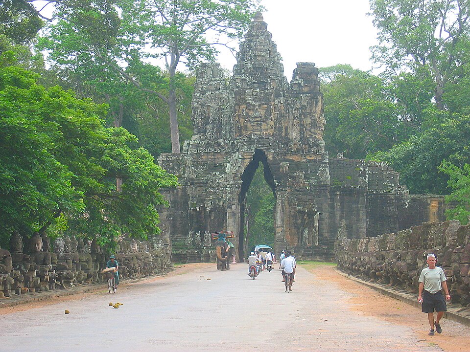 Stone gate of Angkor Thom with a tower bearing four faces, flanked by carved figures along the causeway