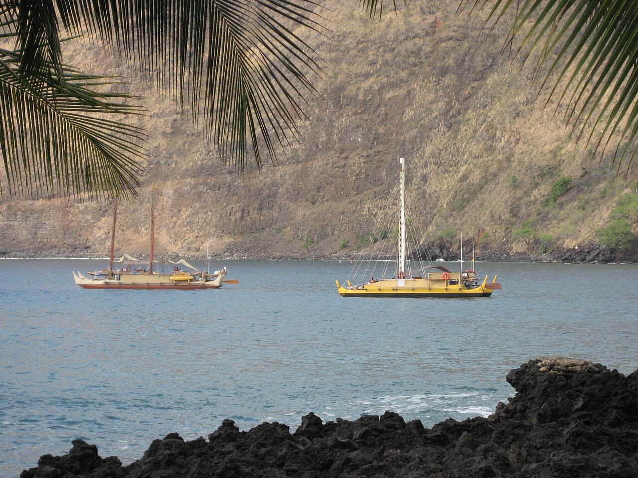 Traditional Polynesian double-hulled voyaging canoes moored in a Hawaiian bay