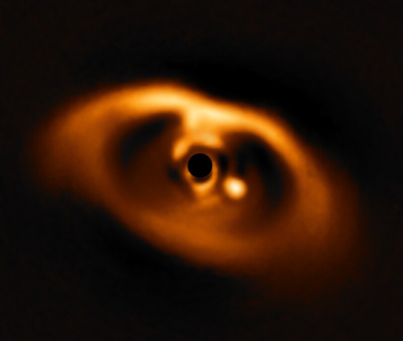 VLT coronagraphic image of the protoplanetary disk around PDS 70, showing a forming planet visible as a bright point to the right of the masked central star