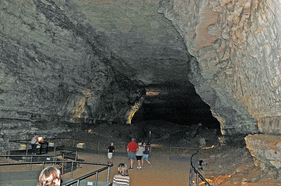 Tourists walking through a large passage inside Mammoth Cave, Kentucky, showing the scale of the dissolved limestone conduit