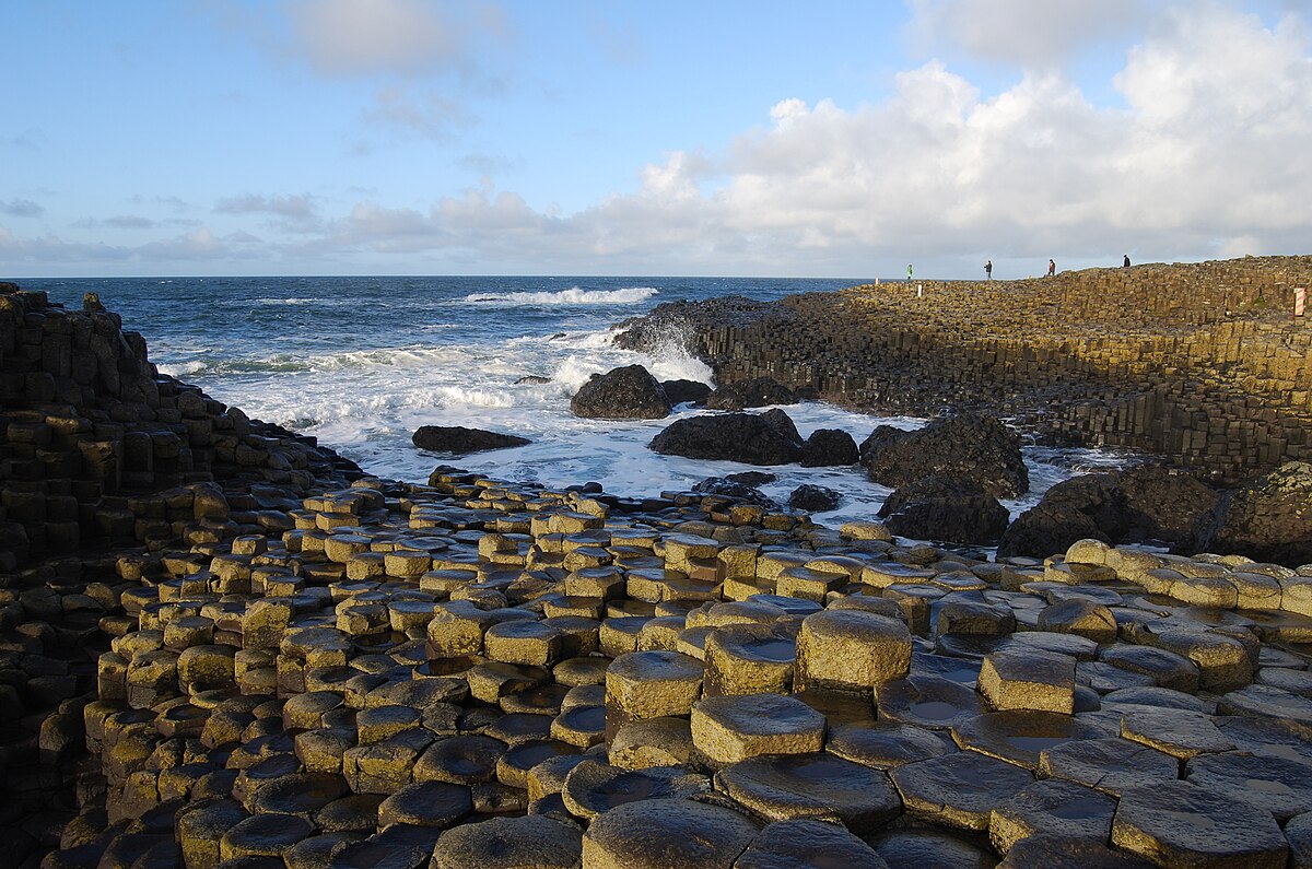 Hexagonal basalt columns at the Giant's Causeway, Northern Ireland, with ocean waves breaking against the shoreline