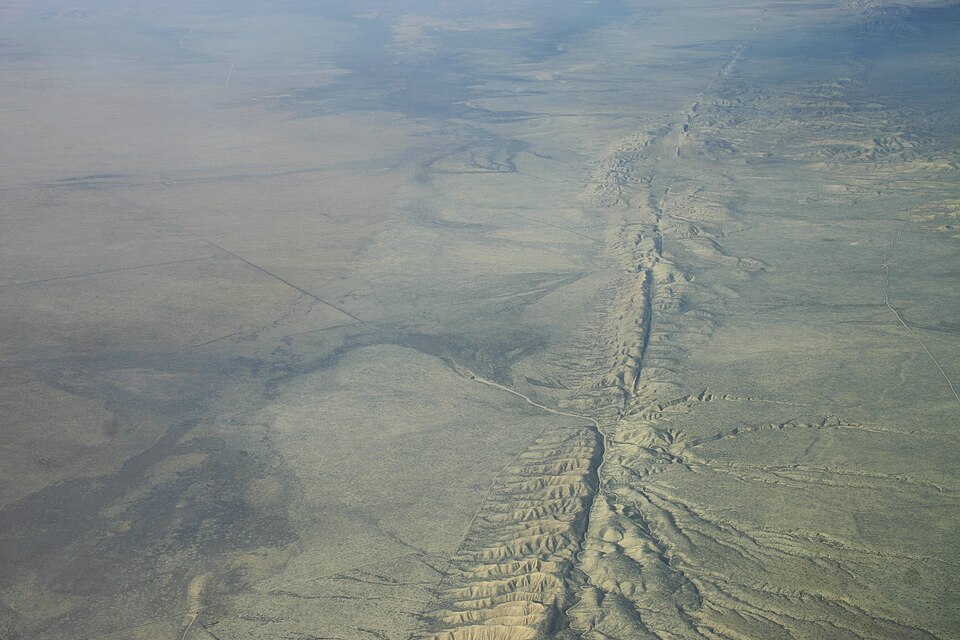 Aerial view of the San Andreas Fault traversing the Carrizo Plain in central California, with the linear fault trace clearly visible across the grassland and offset drainage channels