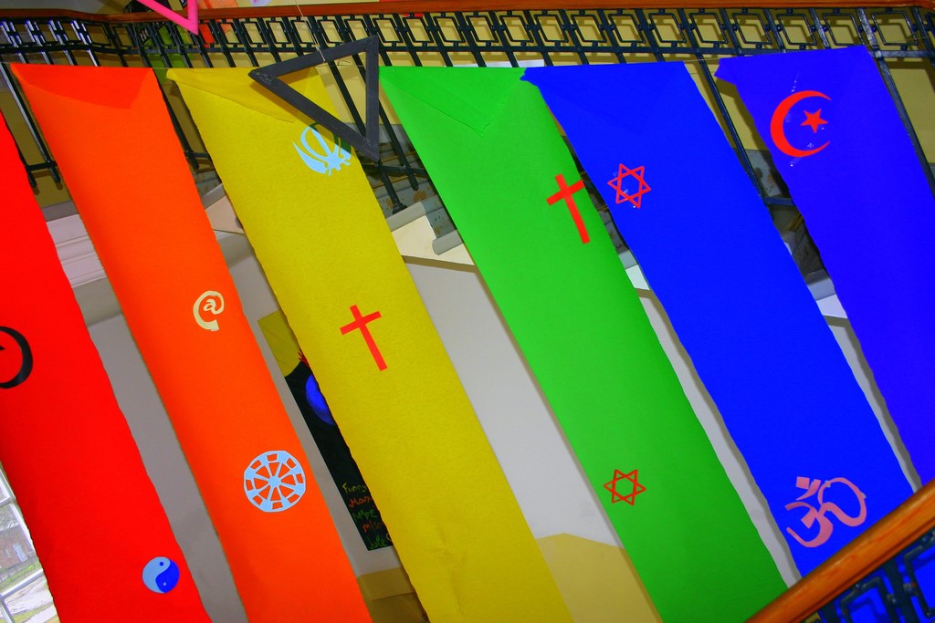 The symbols of the different big world religions on a rainbow - flag